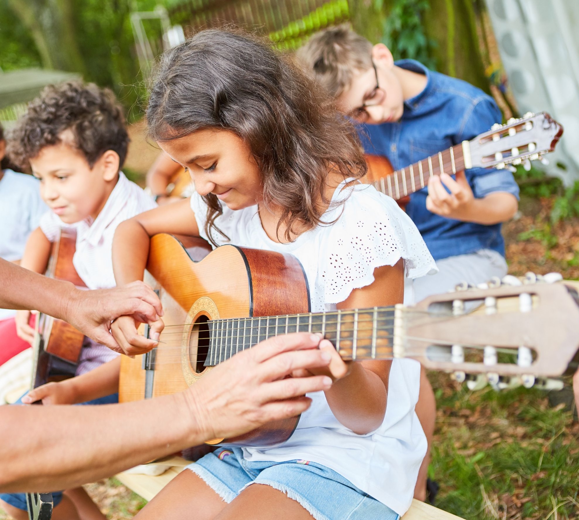 Group guitar lesson with children outdoors